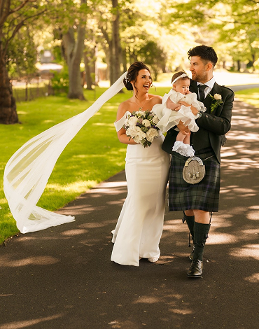 Bride and groom enjoying a joyful moment with their baby in the gardens at Western House Hotel on their wedding day.