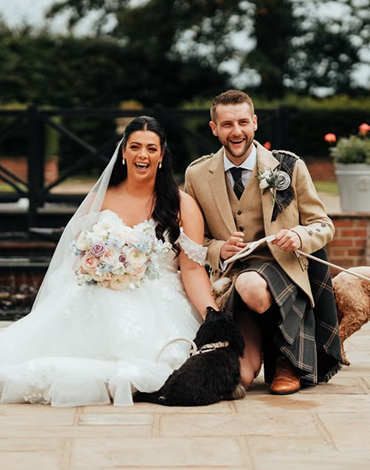 Wedding couple and their dog enjoying a moment by the garden water feature at Western House Hotel in Ayr.